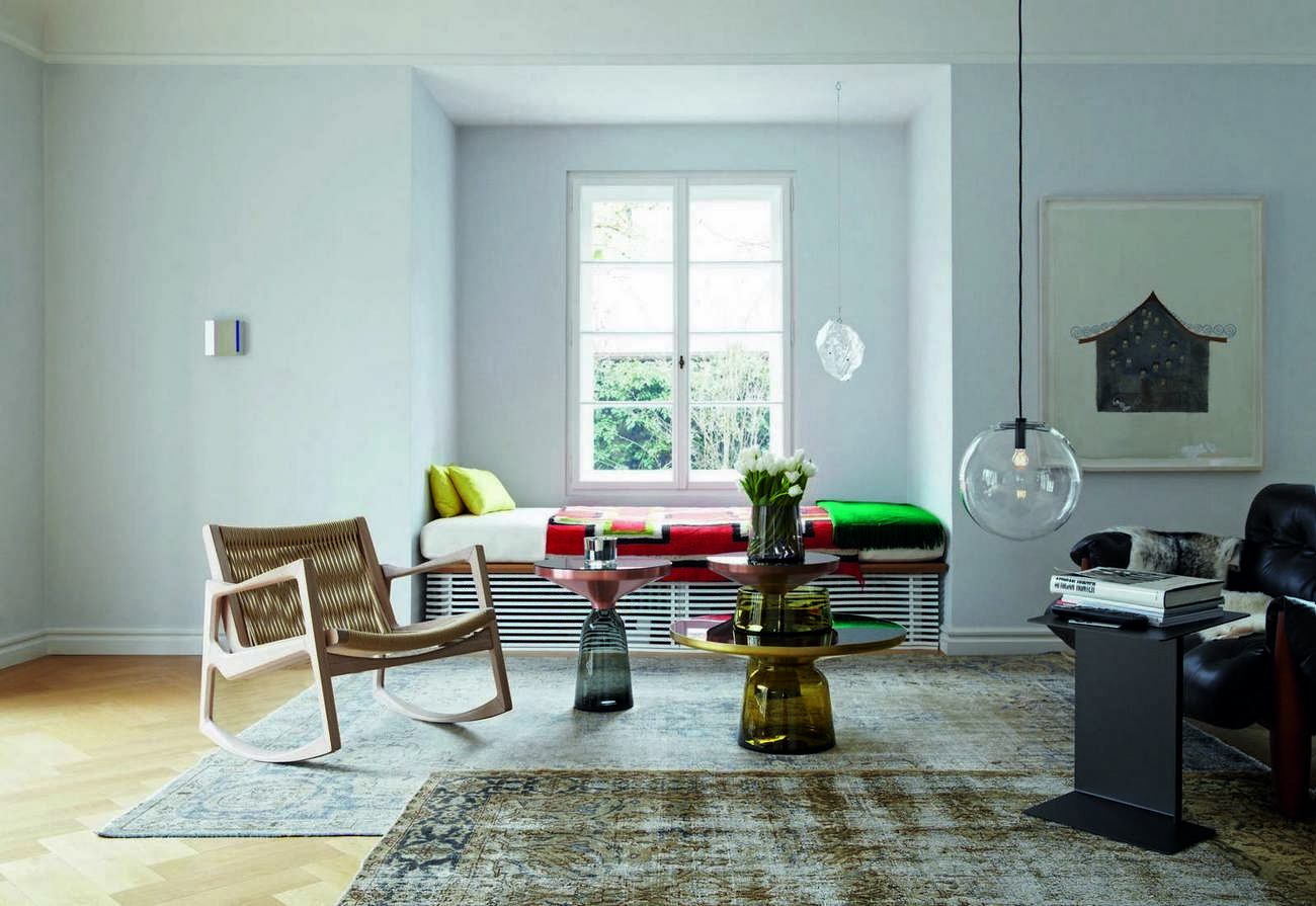 Heller Wohnraum mit ClassiCon Euvira Schaukelstuhl aus hellem Holz und geflochtener Sitzfläche, modernes Möbeldesign.