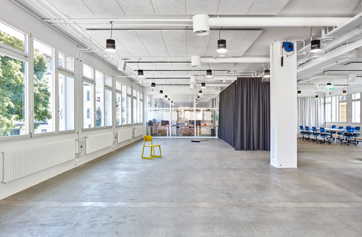 Gelber Tip Ton RE Stuhl von Vitra in modernem Büro mit Betonboden und großen Fenstern.