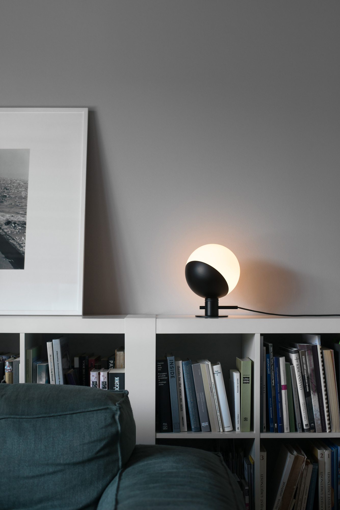 Baluna Tischleuchte von Grupa auf Regal mit Büchern. Moderne Lampe, schwarz-weiß, für Wohnzimmer.