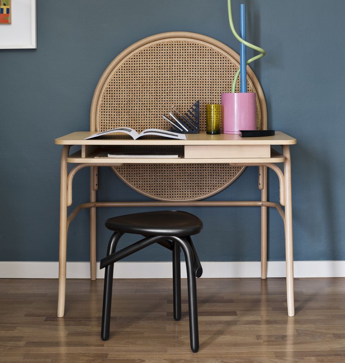 Moderner Schreibtisch aus hellem Holz mit Rattangeflecht und schwarzem Hocker für Arbeitszimmer oder Büro.
