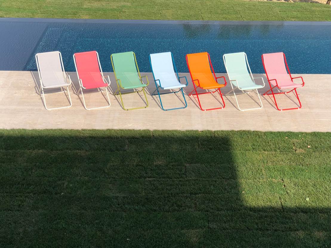 Mehrere farbenfrohe Emu Bahama Liegestühle für den Garten oder Poolbereich im Freien.