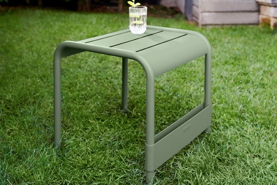 Grüner Luxembourg Beistelltisch von Fermob für den Garten, mit Getränk auf der geriffelten Tischplatte.
