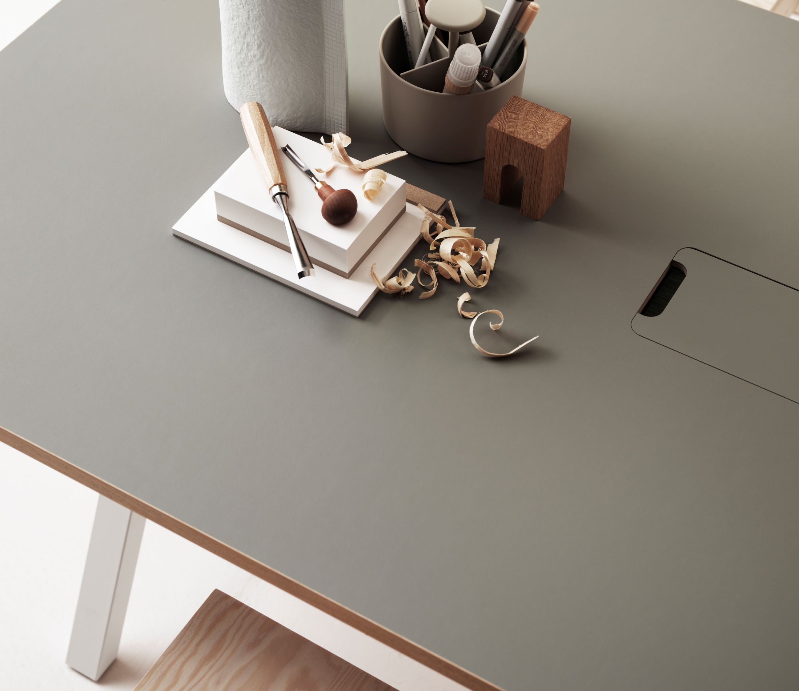 Works Schreibtisch Fix B140cm von String Furniture in Grau mit Werkzeugen und Hobelspänen für kreatives Arbeiten.