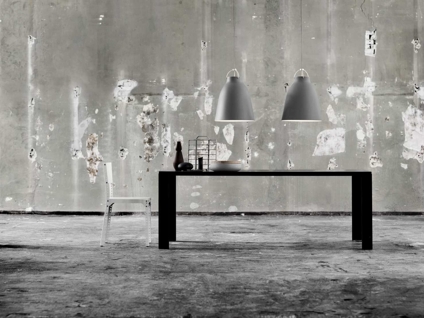 Zwei graue Caravaggio Pendelleuchten von Fritz Hansen über einem Esstisch in einem Loft.