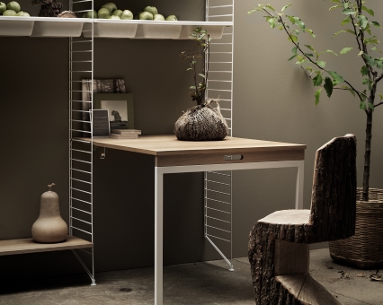 Modernes String Regal mit Schreibtischplatte aus Holz und rustikalem Baumstamm-Stuhl für stilvolles Wohnen.