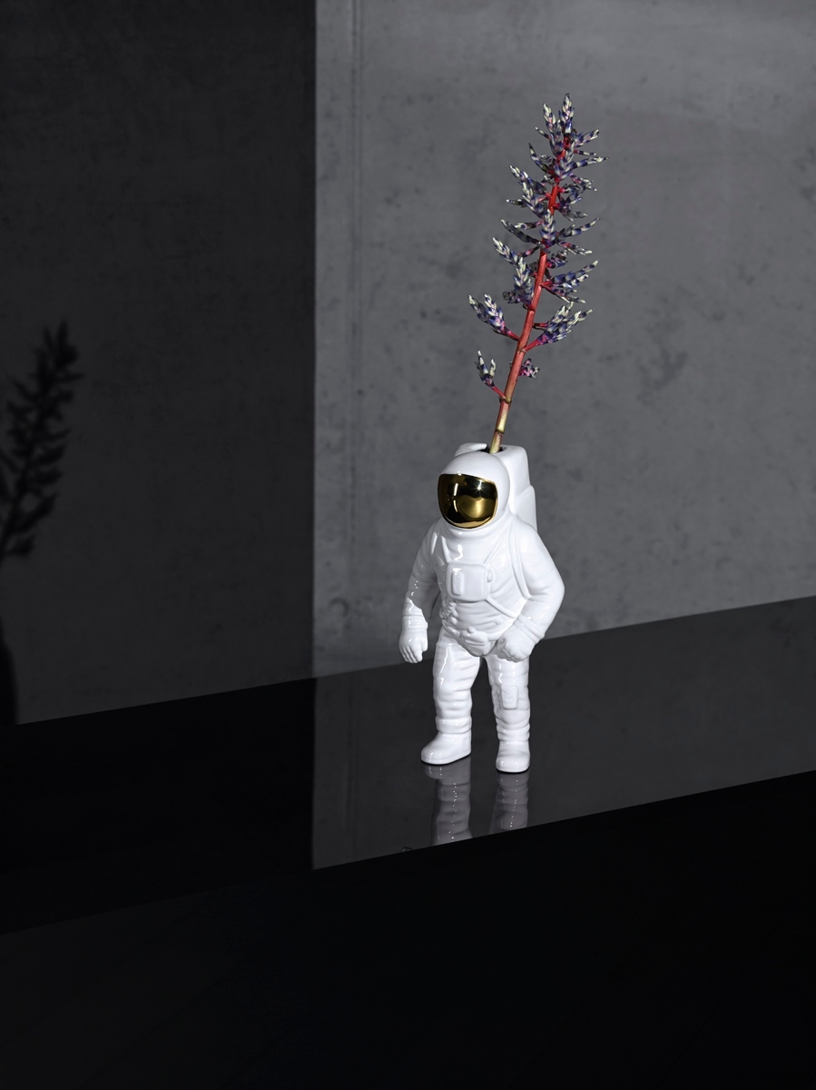Weiße Starman Vase von Seletti in Form eines Astronauten mit Blume auf einem schwarzen Tisch.