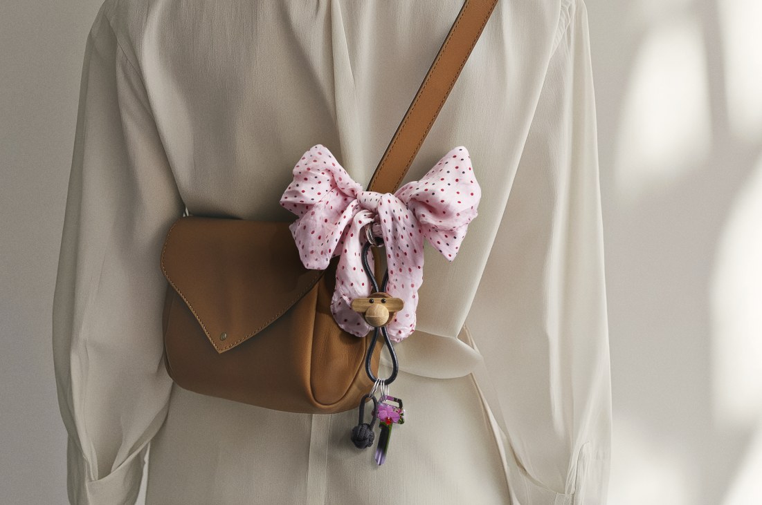 Kay Bojesen Affe Schlüsselanhänger aus Holz und Leder an brauner Handtasche mit Schleife.