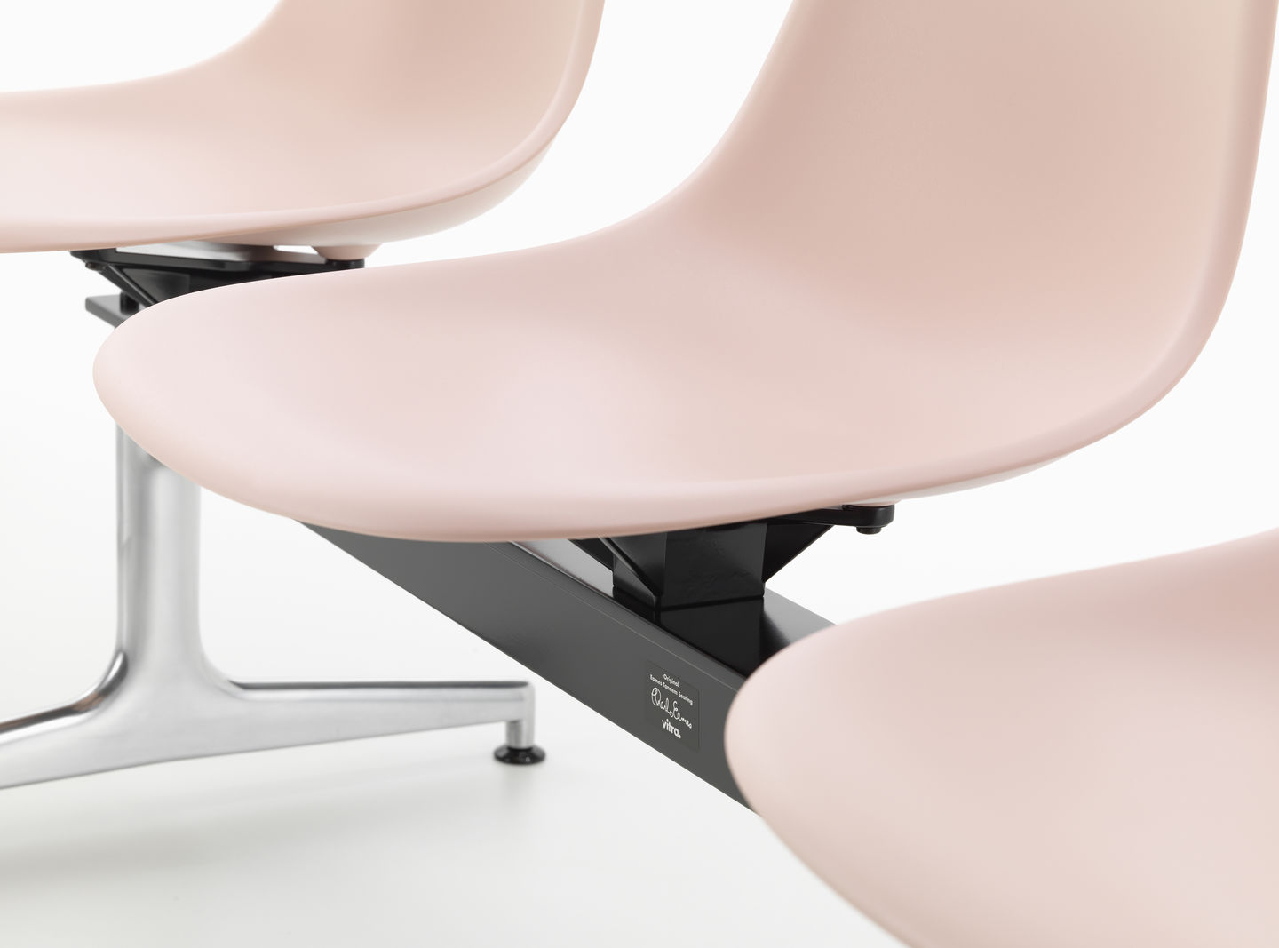 Detailaufnahme: Eames Plastic Side Chair RE auf Traverse von Vitra, Sitzschalen in zartem Rosa.