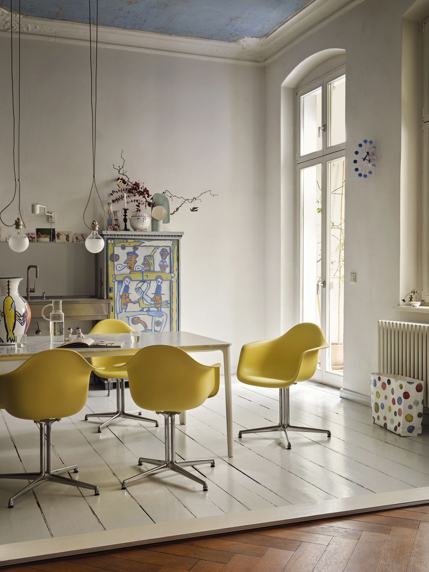 Gelbe Eames Plastic Arm Chairs DAL mit Sitzpolster von Vitra um einen Esstisch.