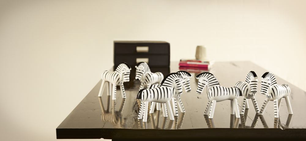 Mehrere Kay Bojesen Zebra Holzfiguren auf einem dunklen Tisch, dekorative Holztiere für Kinder und Sammler.