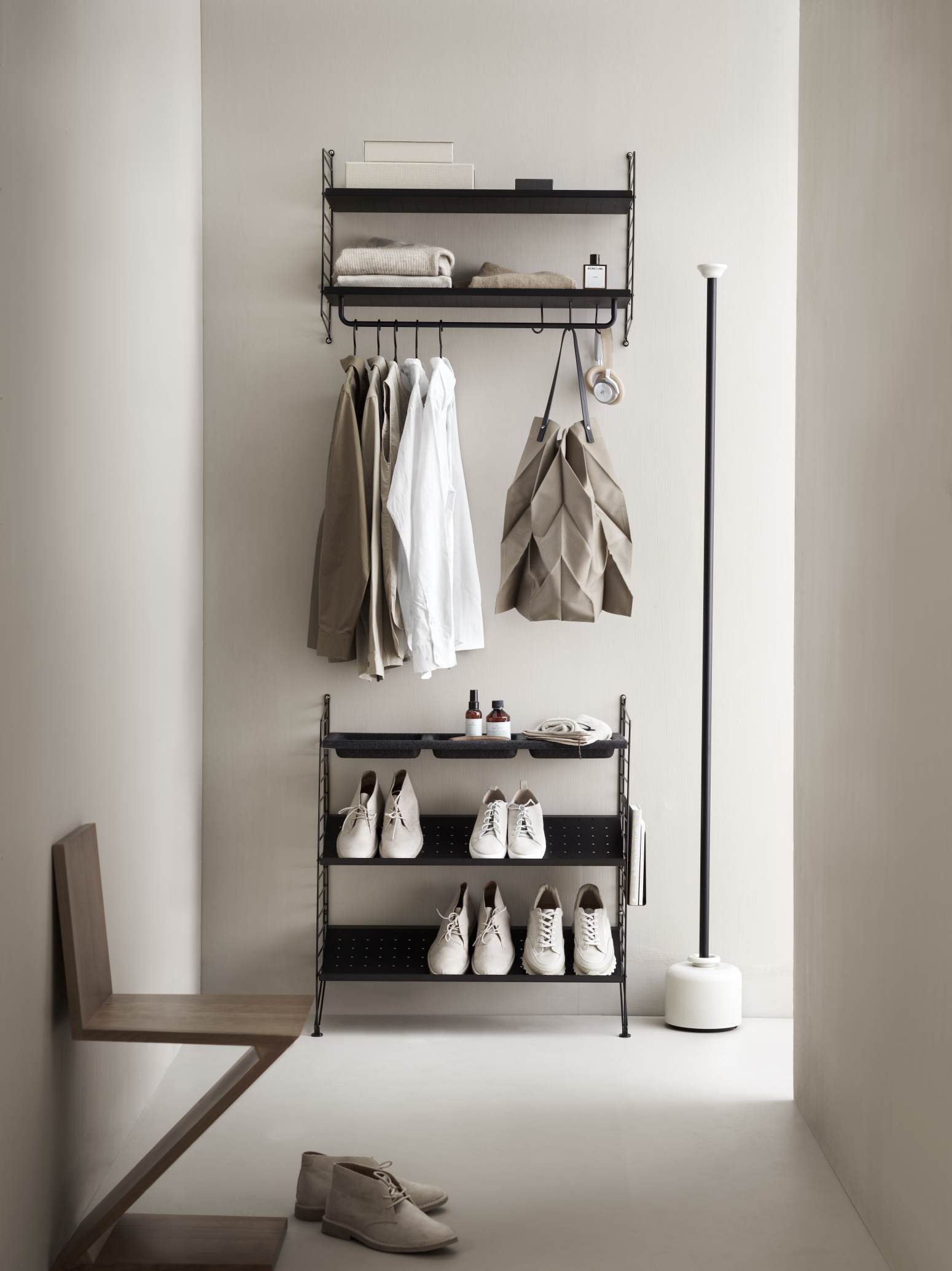 Schwarzes String Regalsystem im Flur mit Kleidung, Schuhen und Accessoires. Wandregal für Ordnung.