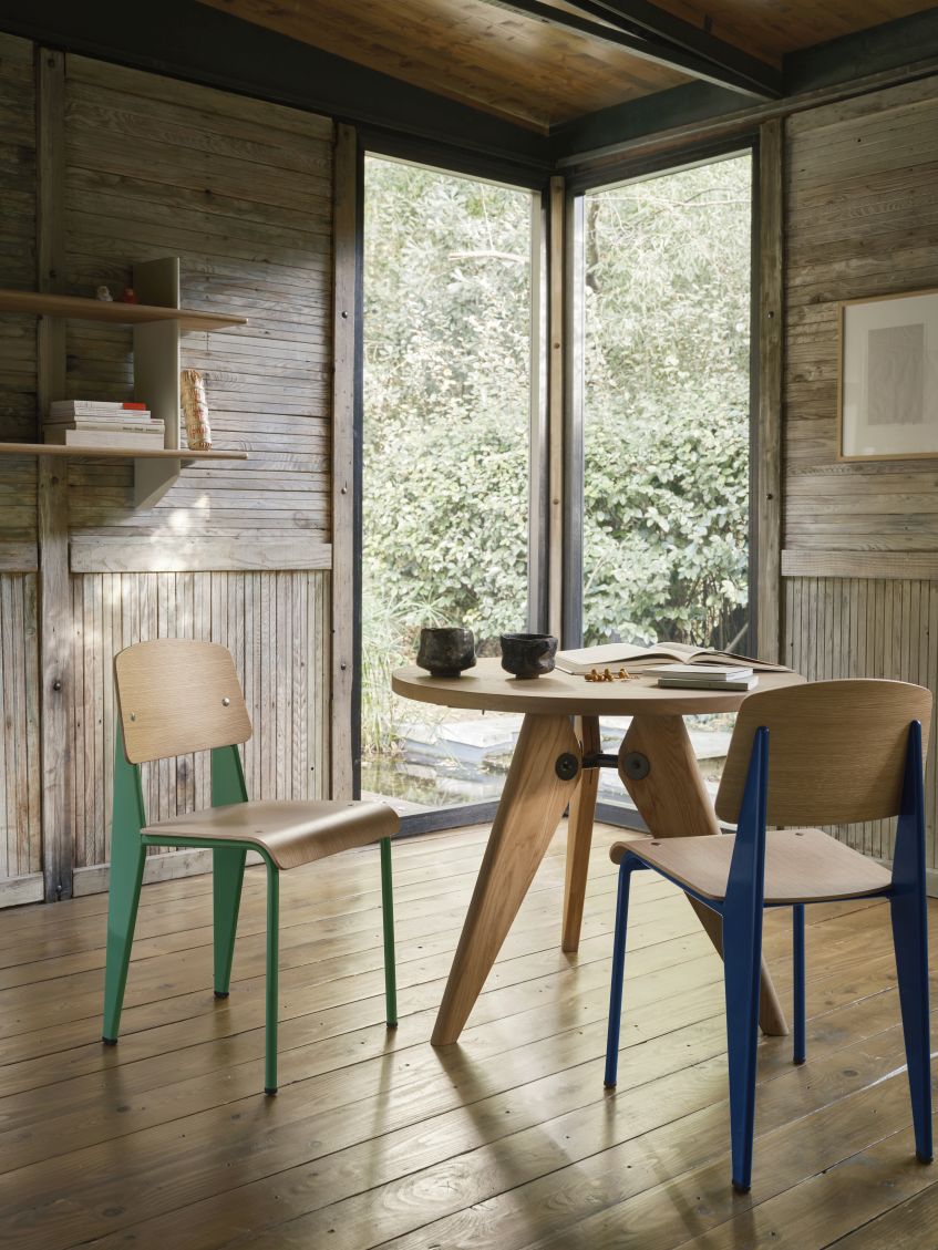 Innenaufnahme mit Vitra-Stühlen und einem Tisch vor einem Fenster mit Blick auf einen Garten.