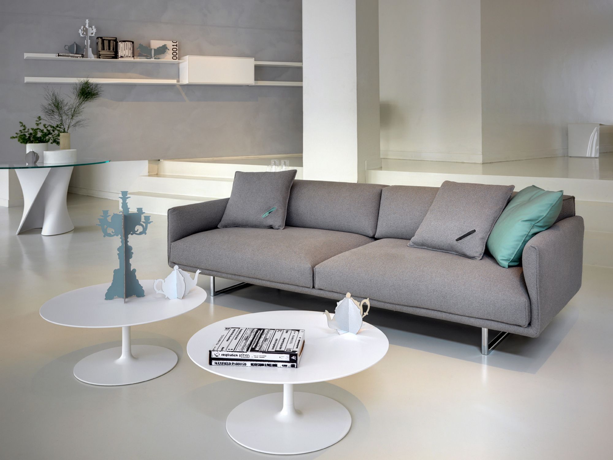 Moderner Wohnraum mit grauem Sofa und zwei weißen Flow Low Table Couchtischen von MDF Italia.