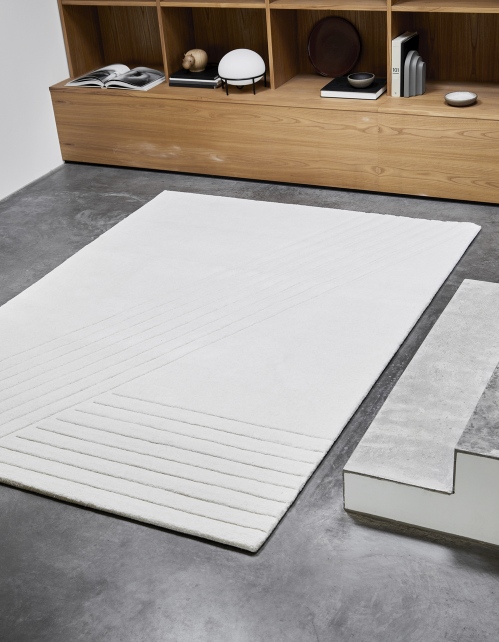Weißer Kyoto Teppich von Woud, 170x240 cm, mit geometrischem Muster auf grauem Boden.