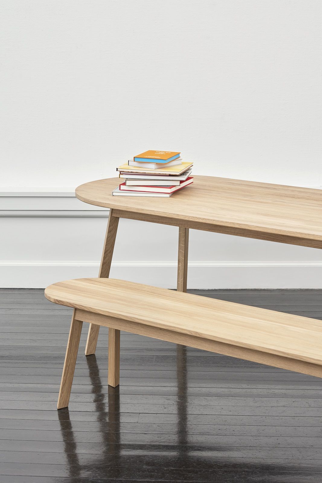 Hay Triangle Leg Table Esstisch aus Eiche mit passender Sitzbank und Bücherstapel.