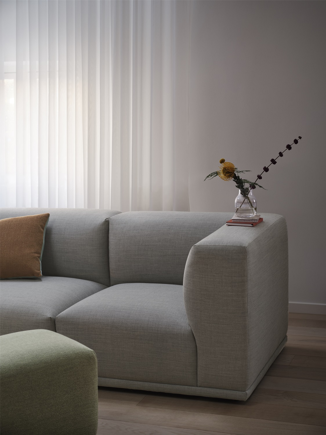 Echo Pouf Hocker von Muuto, hellgrüner Sitzhocker aus Stoff vor grauem Sofa im Wohnzimmer.
