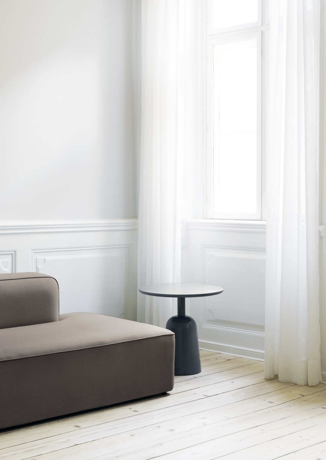 Turn Table Tisch von Normann Copenhagen neben einem Sofa in einem hellen Raum.