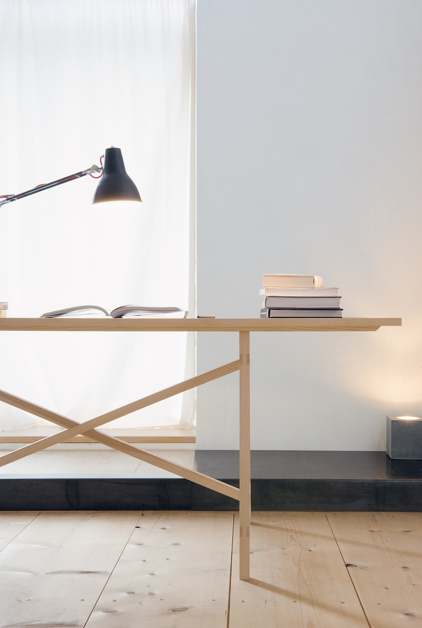 Egon Tisch von Nils Holger Moormann aus hellem Holz mit Lampe und Büchern.