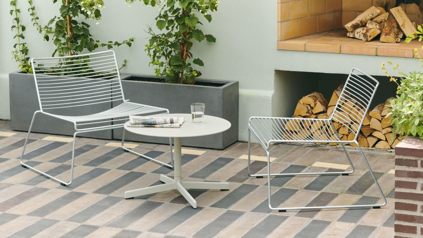 Zwei Hee Lounge Chairs im Garten, moderne Outdoor-Möbel mit minimalistischem Design.