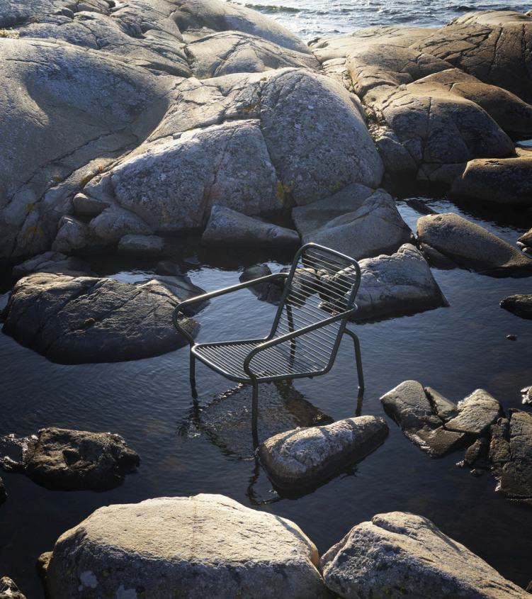 Normann Copenhagen Vig Lounge Chair Outdoor Sessel zwischen Felsen und Wasser, modernes Outdoor-Möbeldesign.