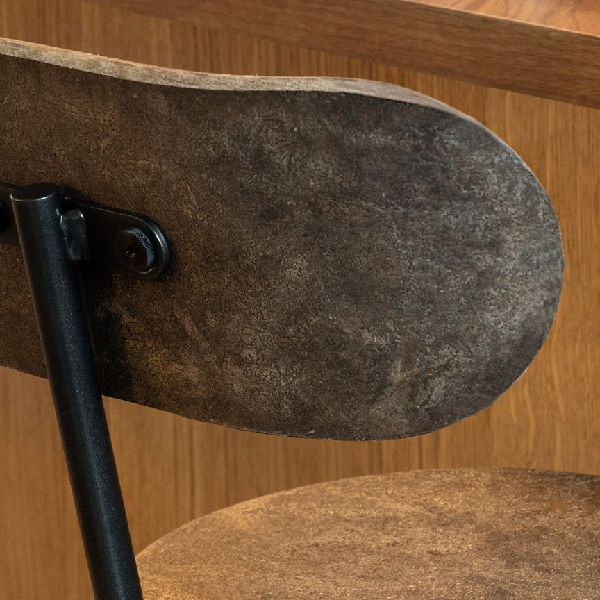 Detailaufnahme: Dunkler Earth Stool Barhocker mit Rückenlehne und schwarzem Metallgestell. Nachhaltige Sitzmöbel für die Bar.
