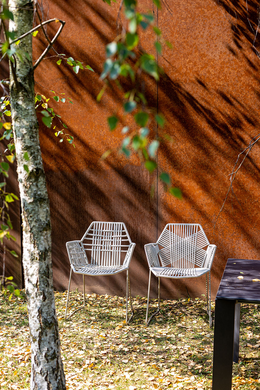 Zwei Tropicalia Armchair Outdoor Stühle von Moroso im Garten, modernes Design mit Armlehnen und Stahlbeinen.