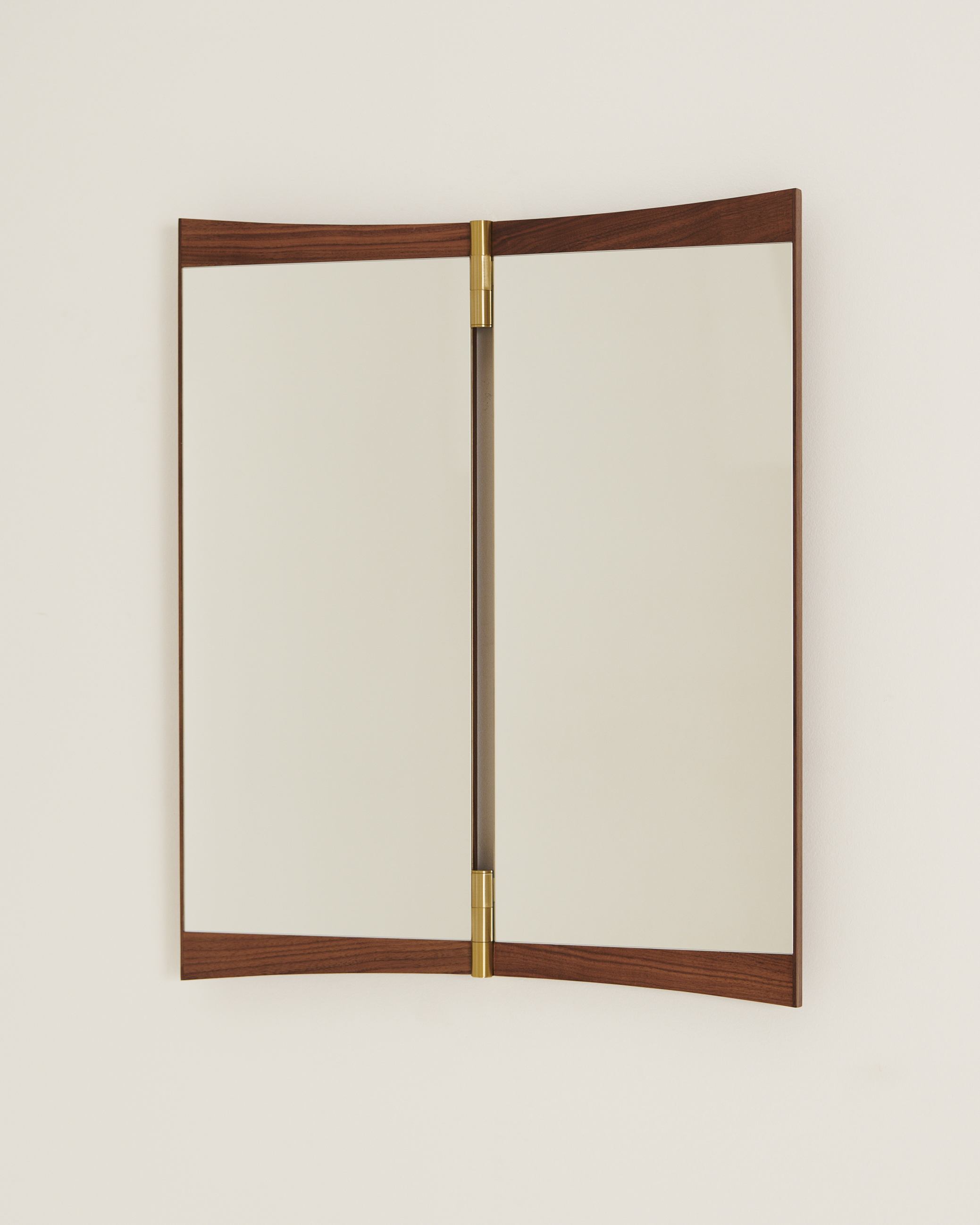 Gubi Vanity Wall Mirror 2 Wandspiegel mit Walnussrahmen und Messingscharnieren an einer weißen Wand.