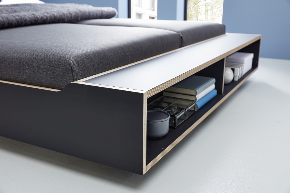 Maude Bett von Müller Möbelwerkstätten mit Stauraum, modernes Designbett mit grauem Stoffbezug und Ablagefächern.