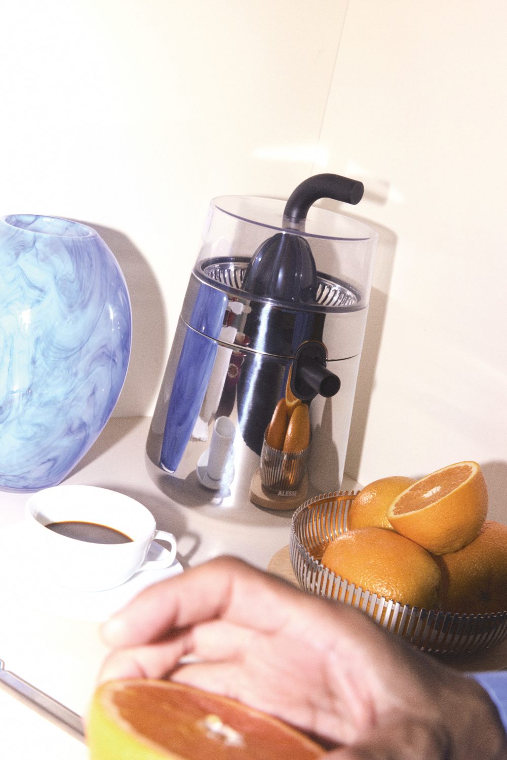 Alessi Zitronenpresse NE02 B Toru: Moderne, elektrische Saftpresse aus Edelstahl mit frischen Orangen.