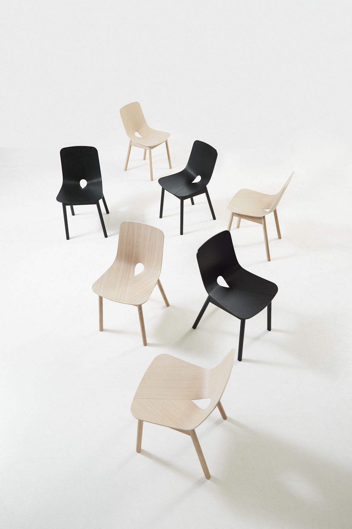 Mehrere Mono Dining Chair Stühle von Woud in Schwarz und Naturholz auf weißem Hintergrund.