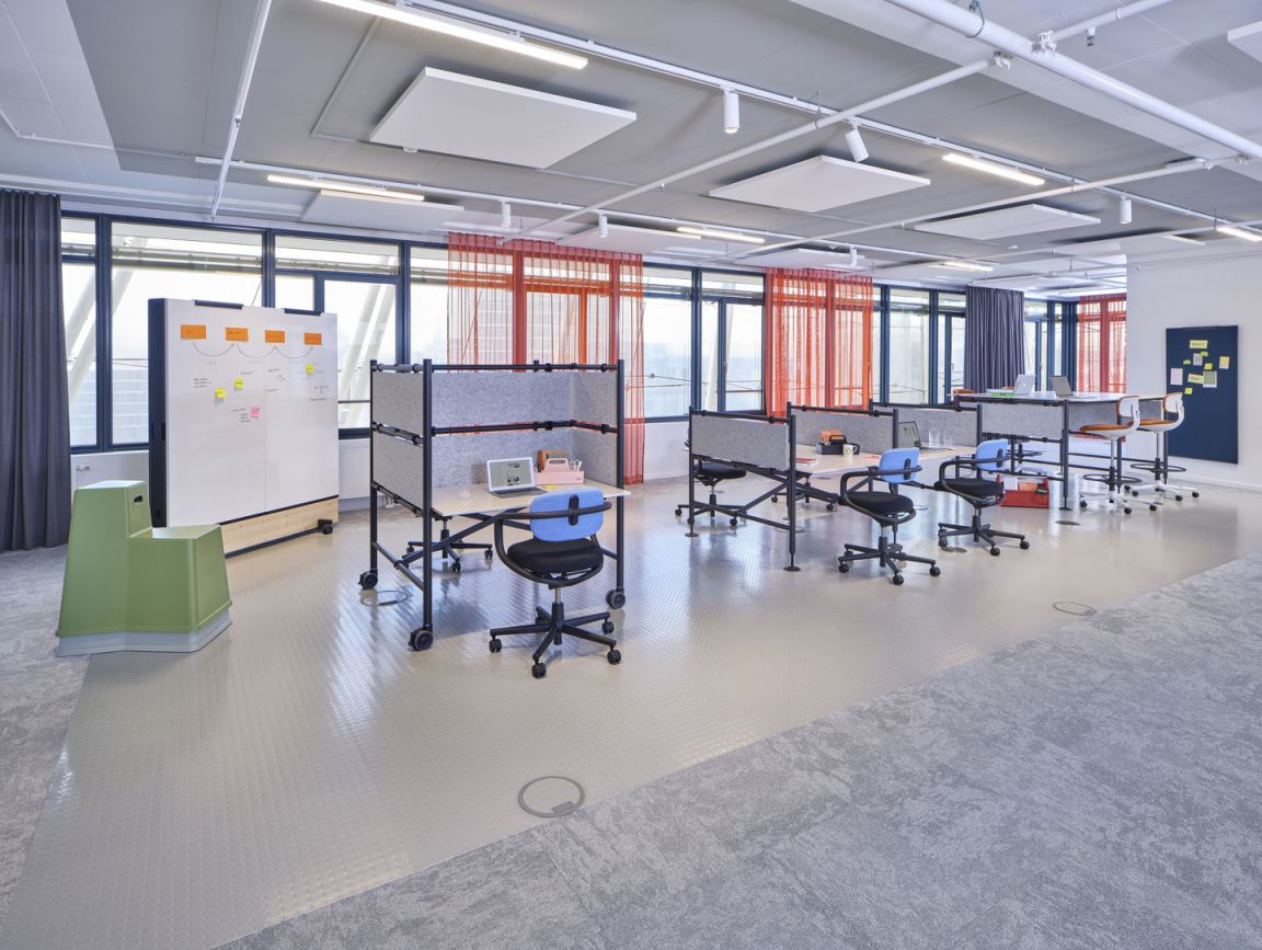 Helles Büro mit mehreren Rookie Bürodrehstühlen von Vitra an Schreibtischen mit Trennwänden.