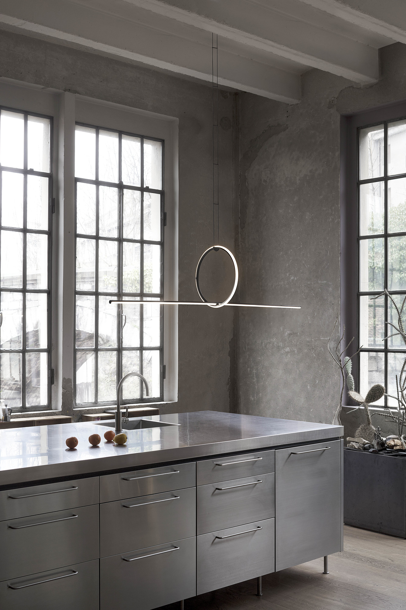Flos Arrangements Pendelleuchte in moderner Küche mit Edelstahlinsel und großen Fenstern für stilvolle Beleuchtung.