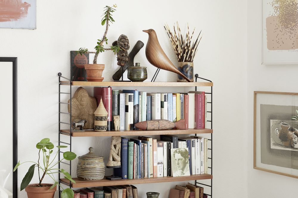 Vollgepacktes Bücherregal aus Holz und Metall mit Büchern, Pflanzen und dekorativen Objekten für Wohnzimmer und Büro.