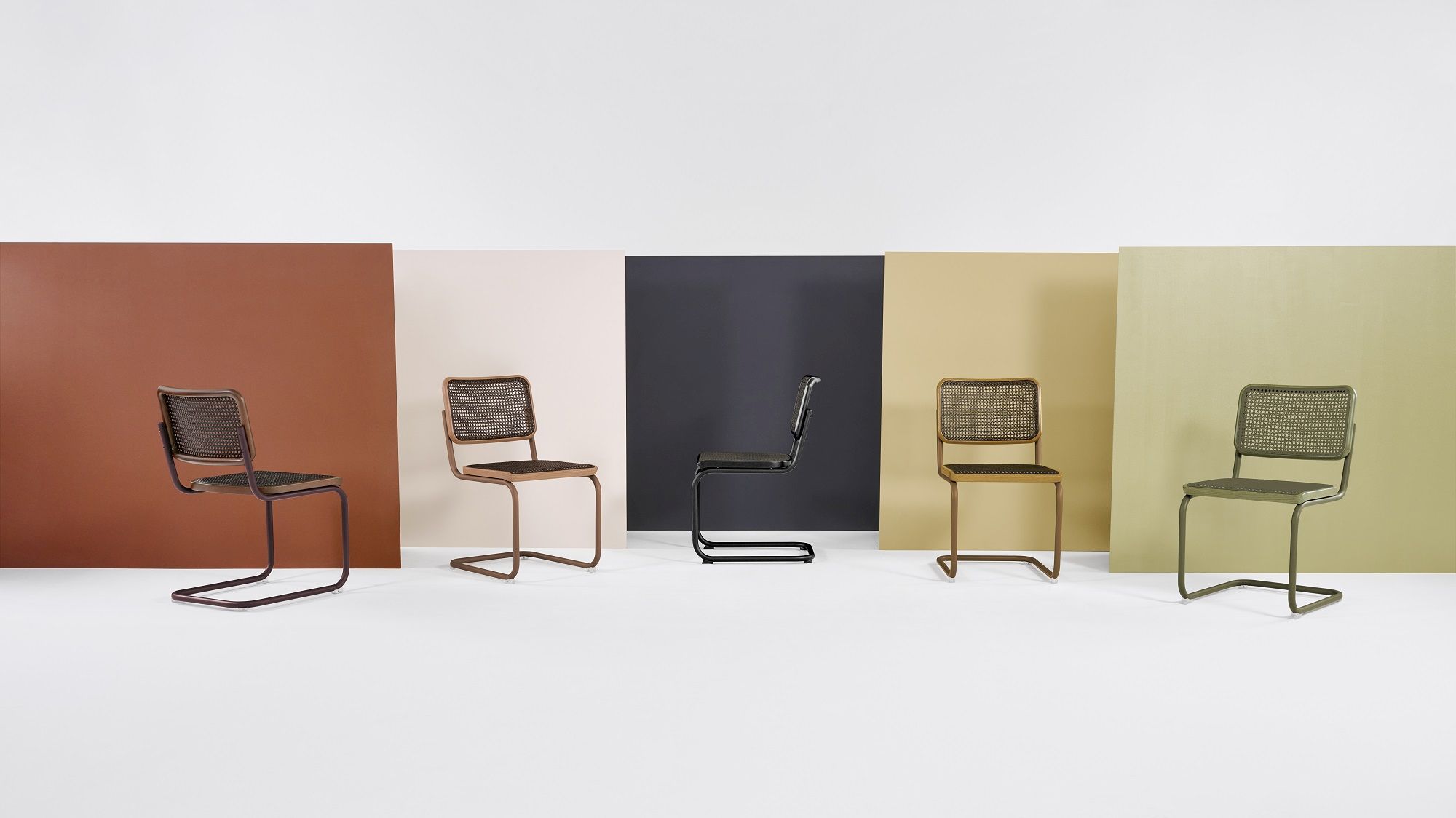 Fünf S 32 V Stahlrohr Freischwinger Thonet Stühle in verschiedenen Farben vor farbigen Hintergründen.