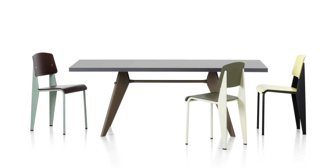 Esstisch mit drei Vitra Standard SP Stühlen in verschiedenen Farben vor neutralem Hintergrund.