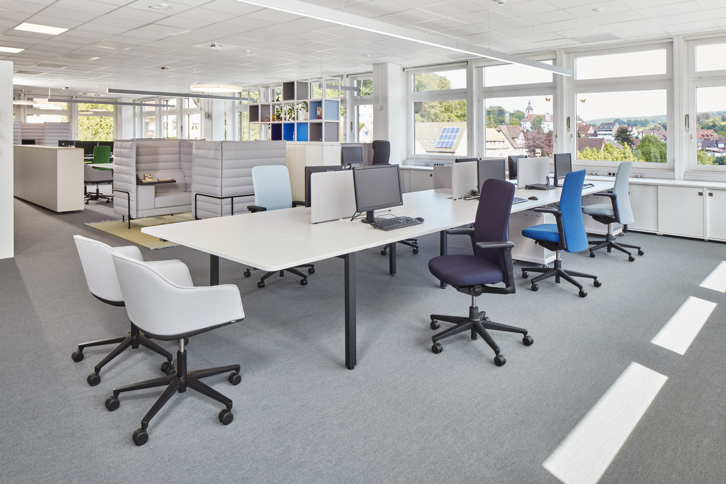 Büro mit Softshell Chair von Vitra, Drehstühle in verschiedenen Farben und langen Schreibtischen.