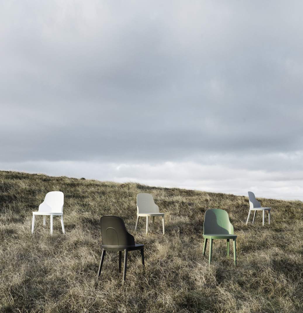 Fünf Allez Stühle von Normann Copenhagen in verschiedenen Farben auf einem Hügel mit trockenem Gras.