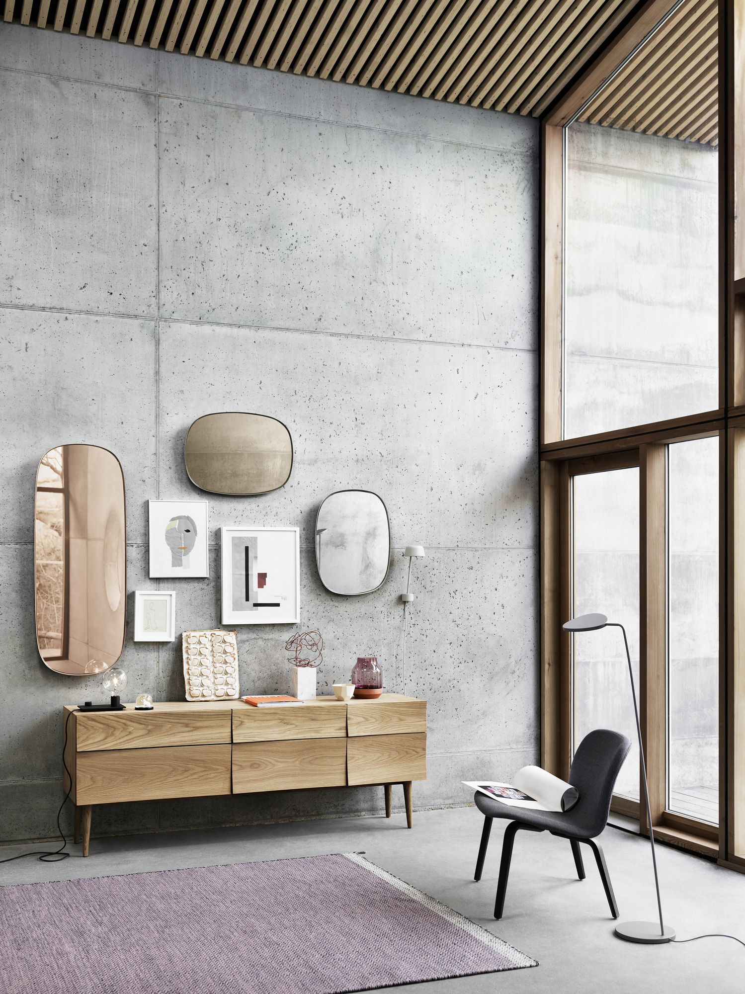 Visu Lounge Chair von Muuto, grauer Polsterstuhl mit dunklen Holzbeinen und Stehlampe im modernen Wohnzimmer.
