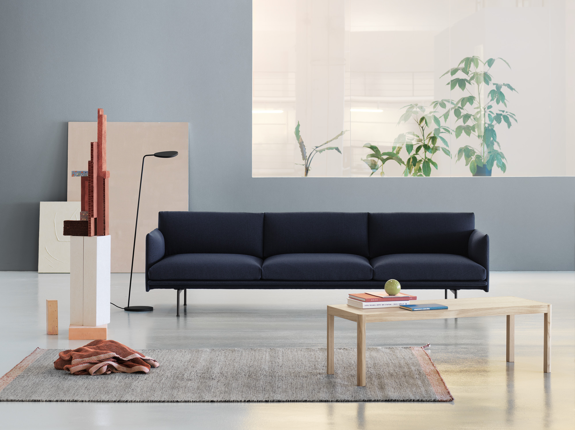 Muuto Workshop Couchtisch aus Eiche vor blauem Sofa und grauem Teppich in modernem Wohnzimmer.