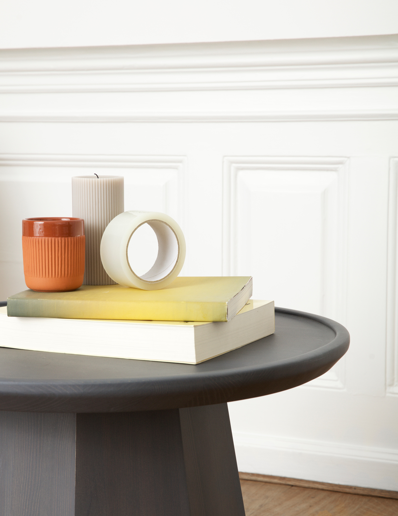 Normann Copenhagen Pine Table Large Beistelltisch in Schwarz mit Kerze, Klebeband und Büchern.