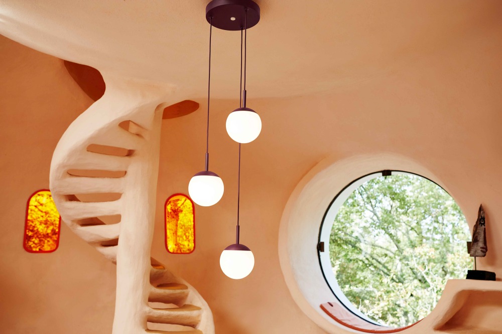 Nahaufnahme der Mooon Triple Pendelleuchte von Fermob, mit drei runden, leuchtenden Kugeln in modernem Interieur.
