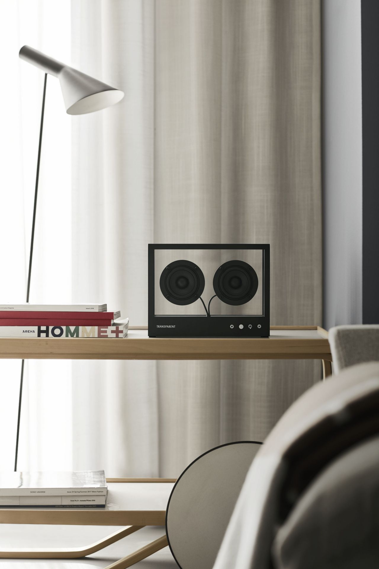 Schwarzer Transparent Speaker auf einem Regal, minimalistisches Design, hochwertige Audio-Technik für audiophile Musikliebhaber.