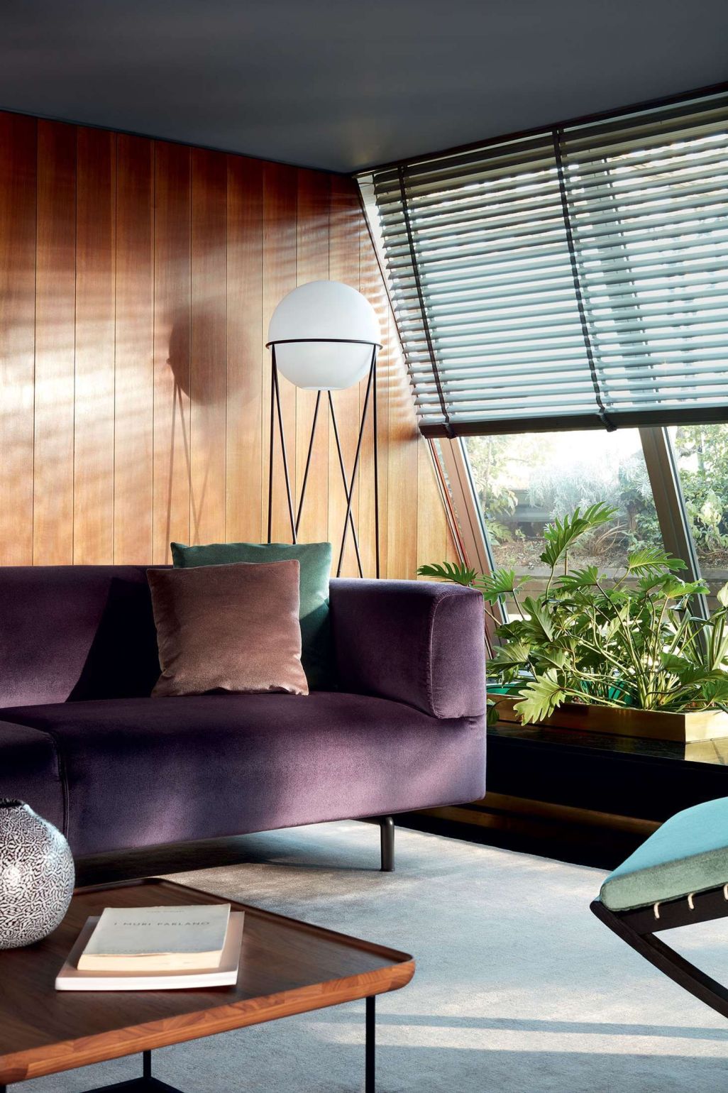 Wohnzimmer mit Cassina 381 Torei Tisch, lila Sofa, Stehlampe und Zimmerpflanze.