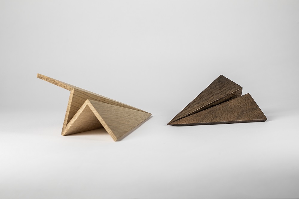 Zwei Maverick Paperplane Holzfiguren, ein helles und ein geräuchertes Eichenholz Papierflugzeug.