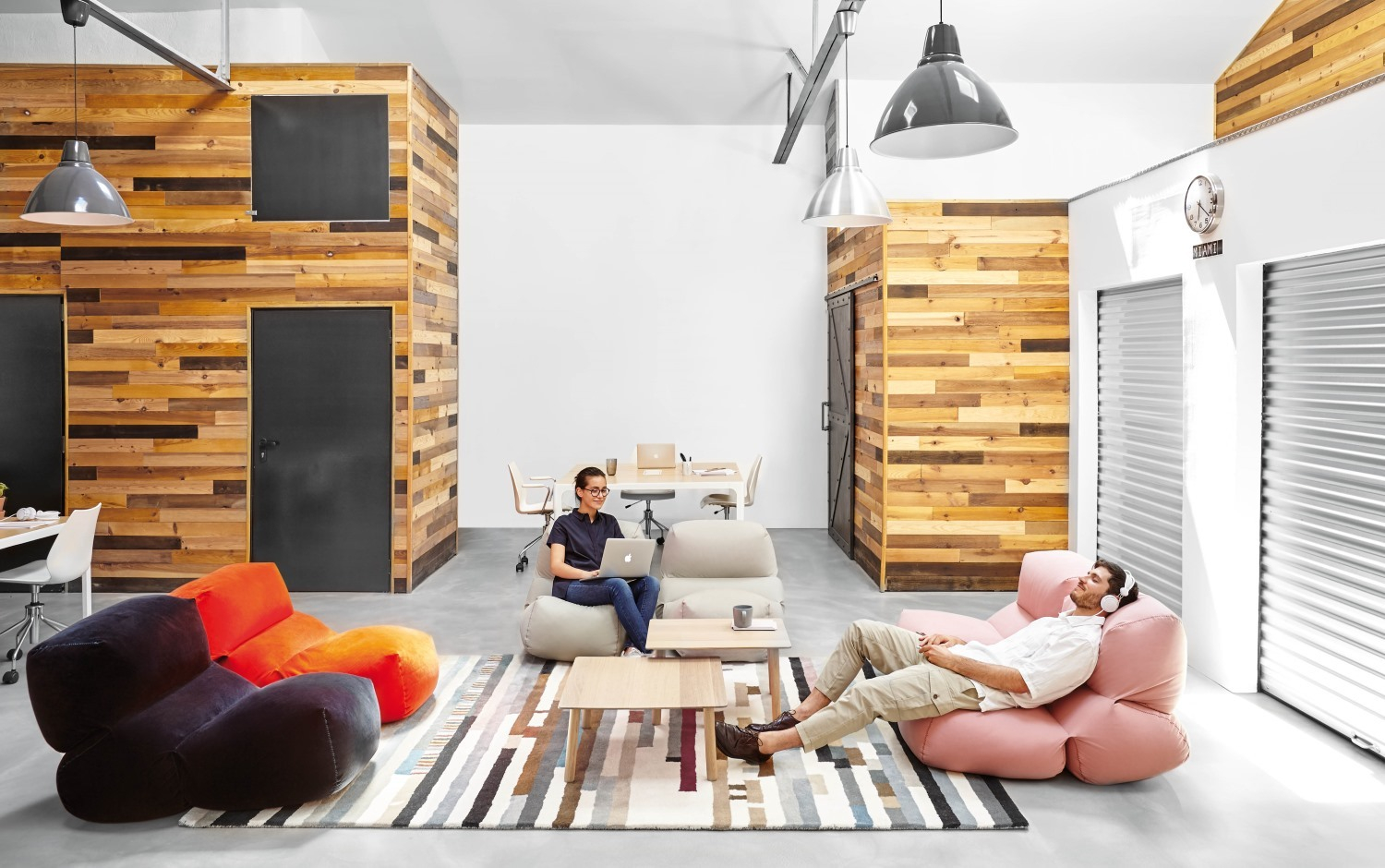 Büro-Szene mit entspannten Personen auf farbigen Sitzkissen, darunter ein Grapy Sitzkissen. Bequeme Baumwoll-Sitzmöbel für modernes Wohnen.