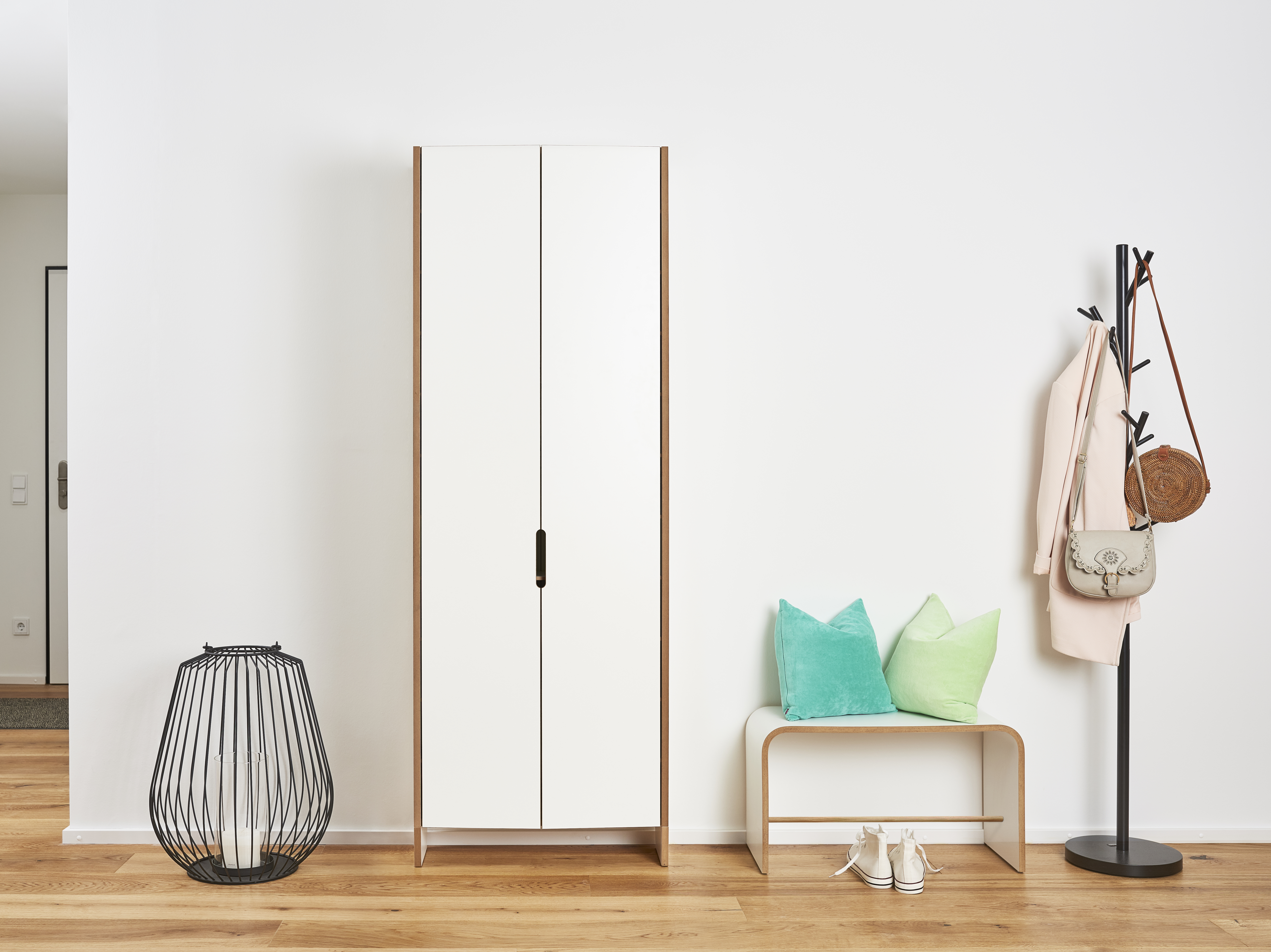 Heller Flur mit weißem Tojo Sit Hocker, Garderobe, Schrank, Dekoration und Holzboden für ein modernes Zuhause.