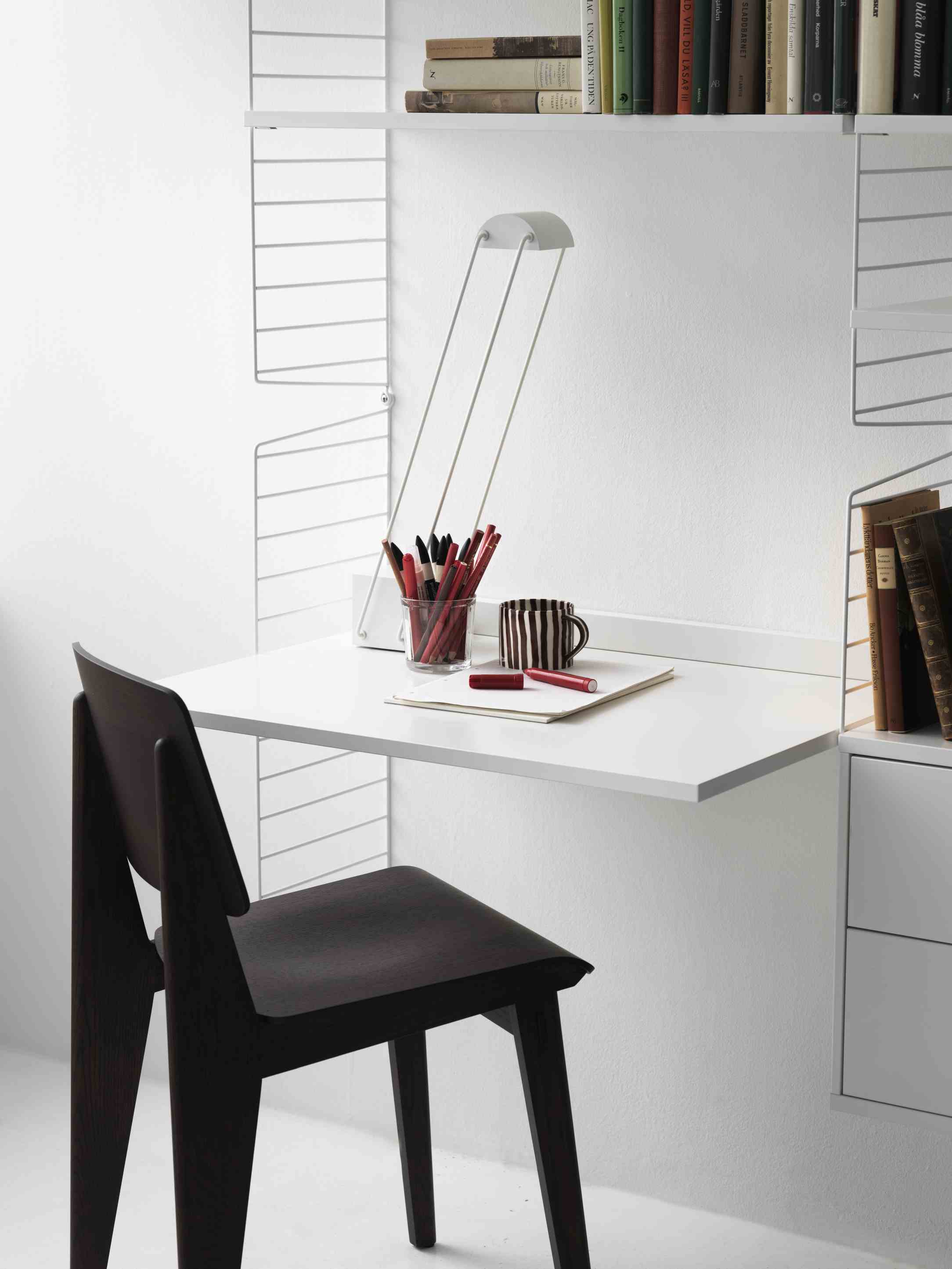 String Regal Arbeitszimmer mit weißem Schreibtisch und dunklem Stuhl. String Furniture Arbeitsplatz für Homeoffice.