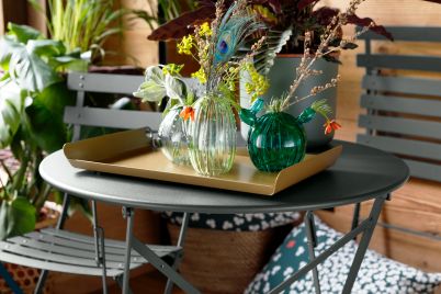 Fermob Bistro Tisch für den Außenbereich, runder Gartentisch aus Metall mit Dekoration auf einer Terrasse.