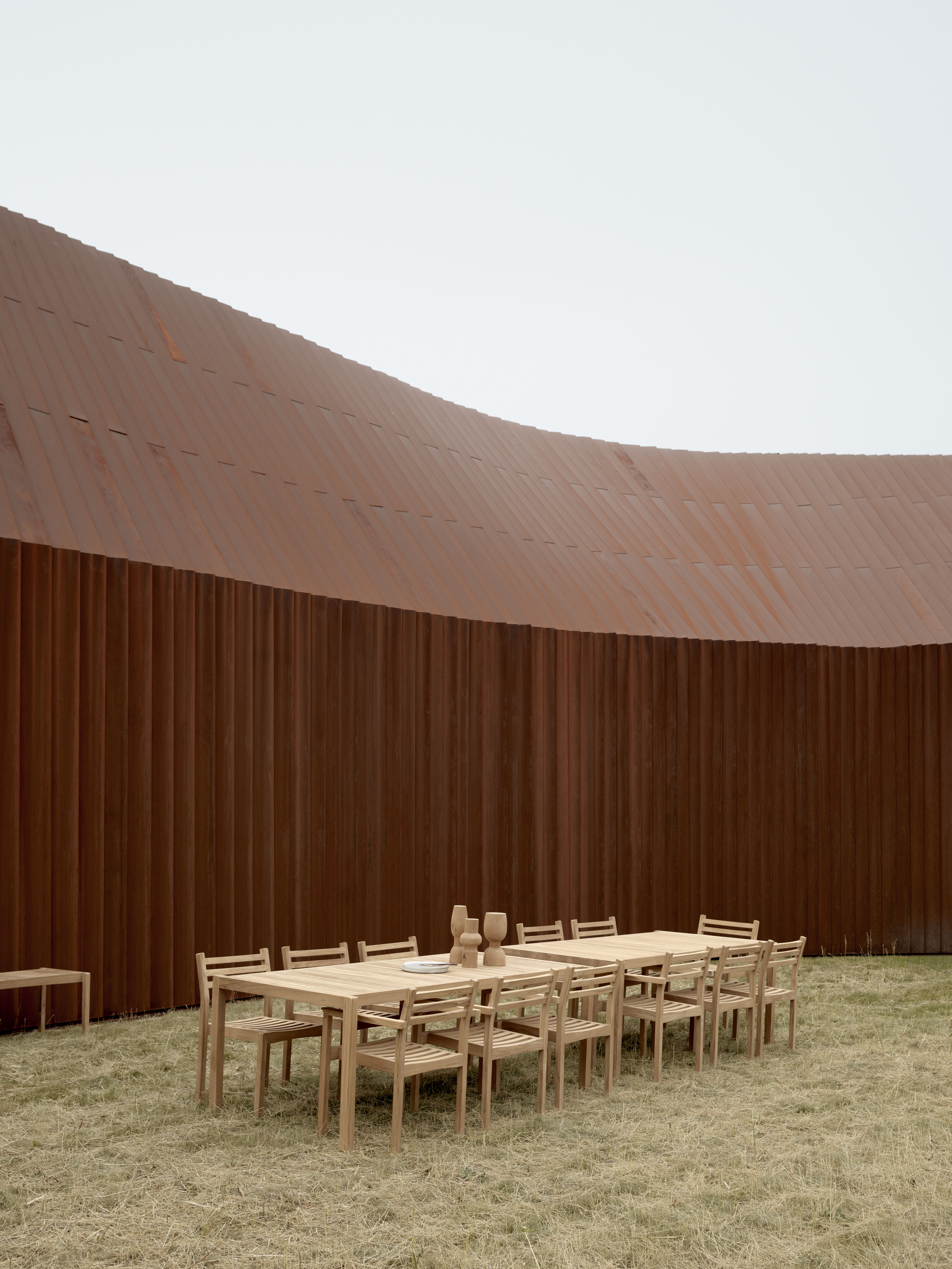 AH502 Armlehnstuhl Teak Outdoor von Carl Hansen & Søn mit passendem Tisch im Garten.