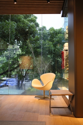 Beiger Schwanensessel von Fritz Hansen mit PK91 Falthocker im modernen Wohnzimmer mit Blick ins Grüne.